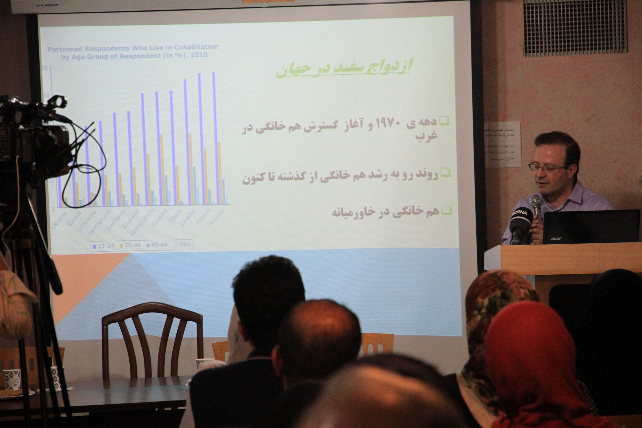 A speaker presenting a projected chart to an audience.